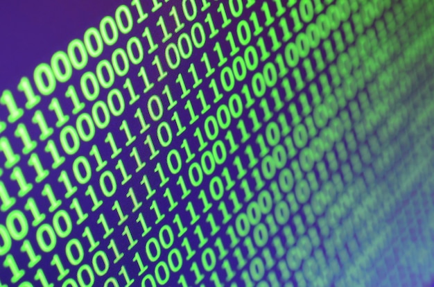 Tiro macro del código binario en el monitor de una computadora de oficina.