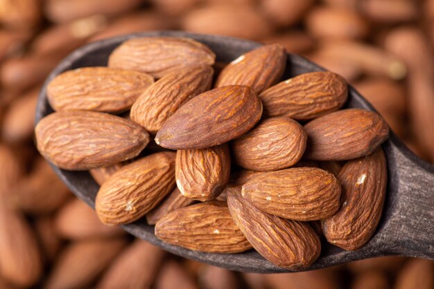 Tiro macro de sabrosas nueces almendras en cuchara de madera oscura Cocinar con concepto de almendras sabrosas nueces frescas