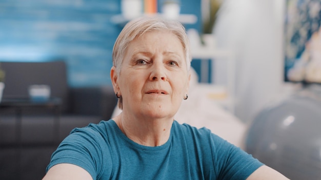 Tiro de mano de pensionista haciendo ejercicio de entrenamiento en casa. Retrato de mujer senior entrenando con equipamiento deportivo para fitness y salud. Cerca de la persona mayor haciendo ejercicio.