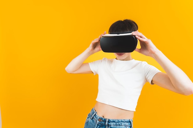 Tiro médio de uma mulher usando óculos vr e segurando-os com as mãos fundo brilhante