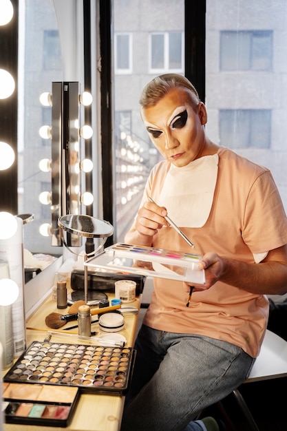 Foto tiro médio drag queen colocando maquiagem