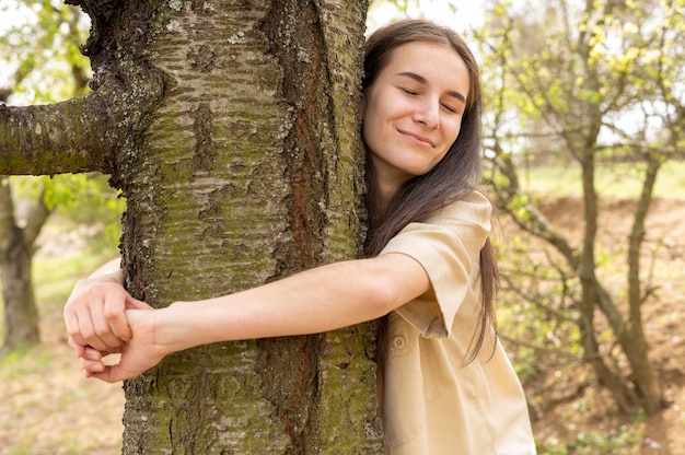 Foto tiro medio mujer abrazando árbol