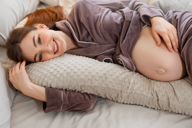 Foto tiro medio mujer embarazada acostada en la cama