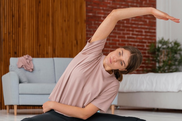 Foto tiro medio mujer estirando en el piso