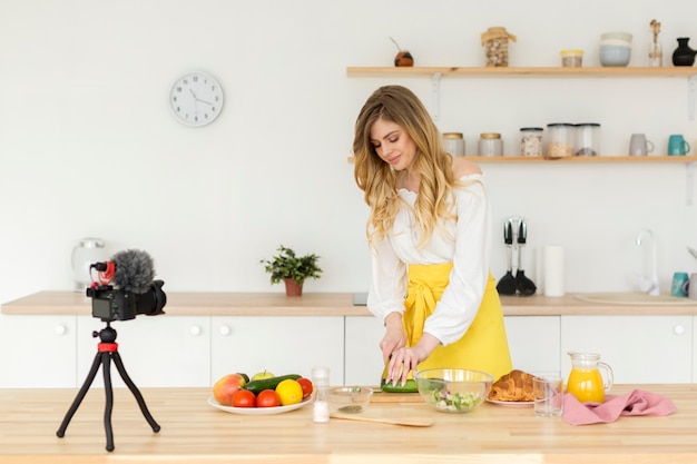 Foto tiro medio mujer grabando en la cocina