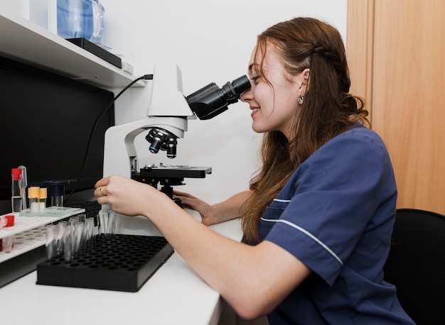 Tiro medio mujer mirando a través del microscopio