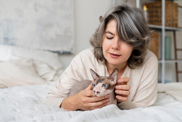 Foto tiro medio mujer senior y gato en la cama