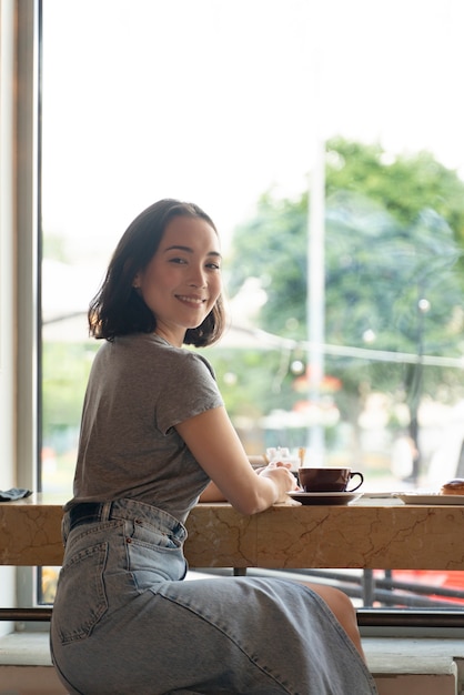 Foto tiro medio mujer sonriente sentada con café