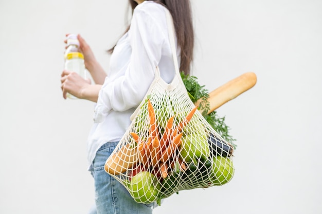 Tiro medio mujer sosteniendo reutilizable con bolsa de supermercado afuera