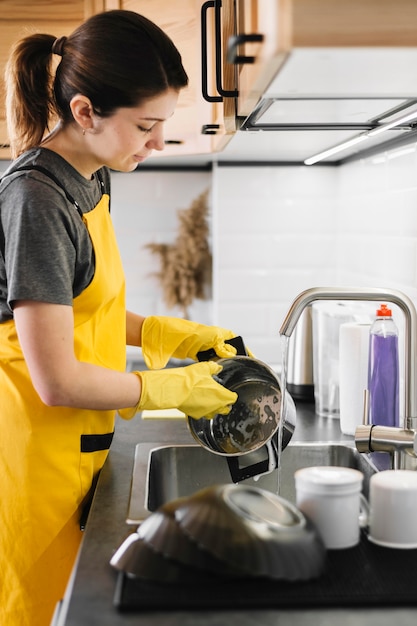 Tiro médio mulher lavando pratos