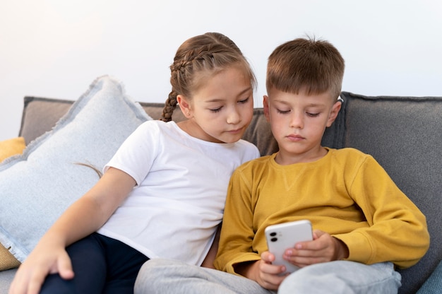 Foto tiro medio niña y niño con teléfono