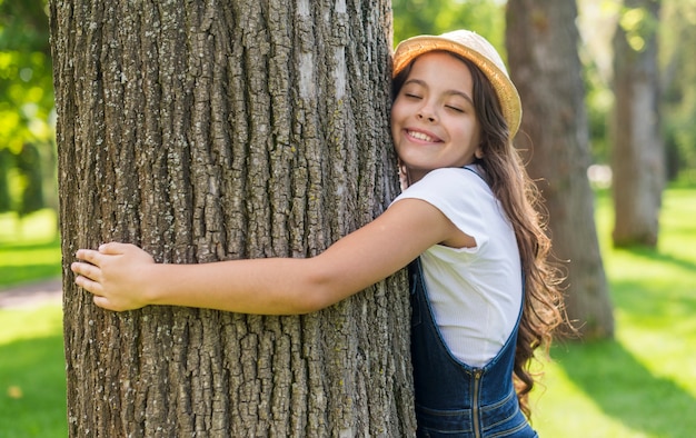 Tiro medio niña sonriente abrazando un árbol
