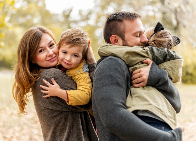 Tiro medio padres felices abrazando a los niños