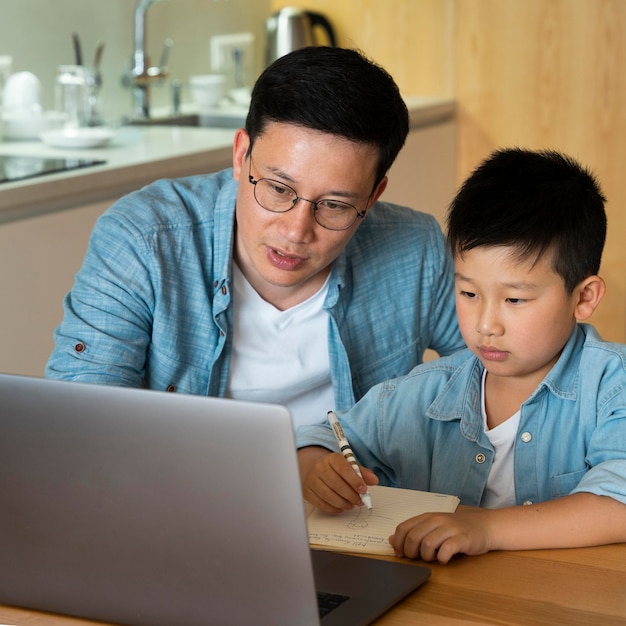 Tiro médio, pai e filho fazendo lição de casa
