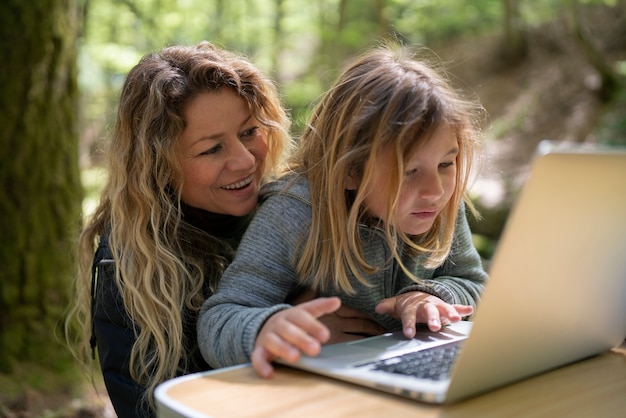 Tiro médio sorridente mãe e menina com laptop