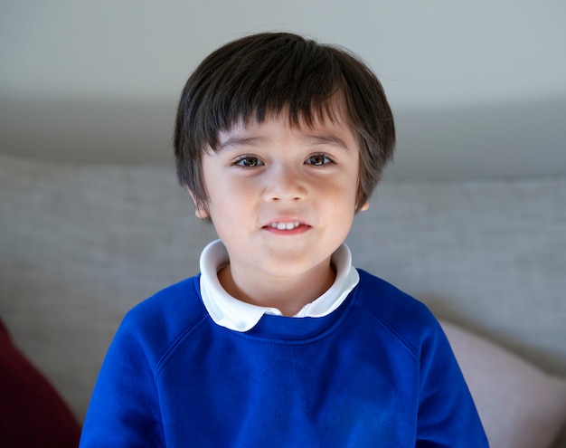 Tiro na cabeça da criança da escola, retrato feliz 6-7 anos de idade criança com rosto sorridente, candid tiro mestiços saudável rapaz relaxando em casa. Conceito positivo de crianças