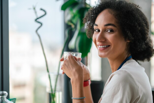 Tiro na cabeça de uma mulher bonita sorridente tomando café