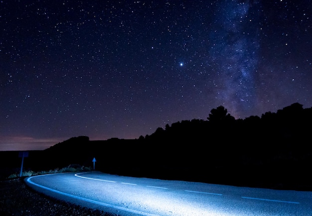 Tiro noturno da via láctea e estrelas em uma estrada de alta montanha