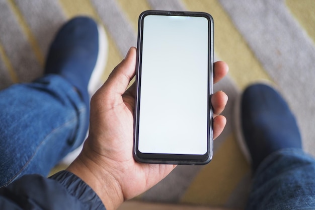 Tiro POV da mão do jovem usando telefone inteligente com tela vazia