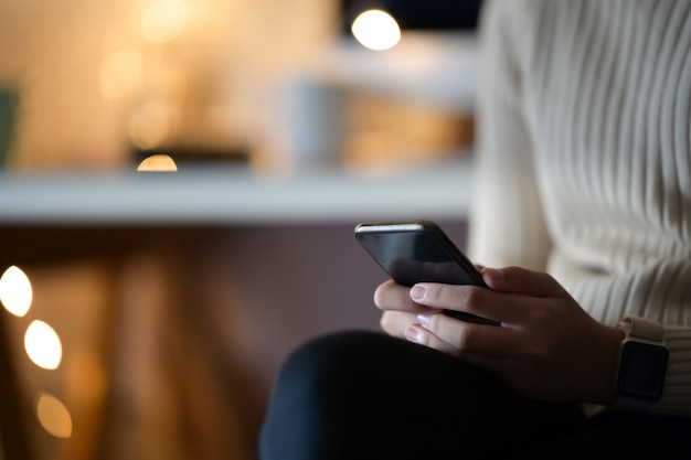 Tiro recortado de mulher usando telefone celular sentado no café