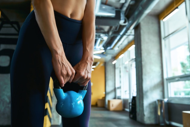 Tiro recortado de entrenamiento con pesas de una mujer atlética fuerte ejercicio con mancuernas en el gimnasio industrial