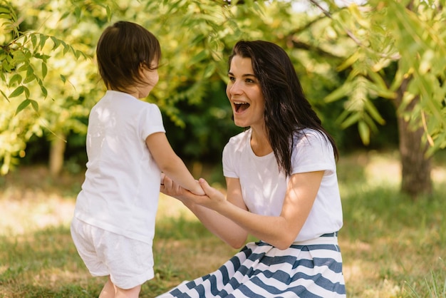 Tiro sincero de mãe linda feliz e seu filho fofo brincando ao ar livre abraçados mostram o amor Mãe e seu filho bonito brincam no parque Retrato de bom relacionamento em família Maternidade