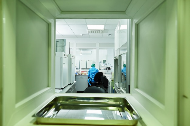 Foto tiro trasero del científico médico en traje protector y sombrero desechable médico trabajando en laboratorio