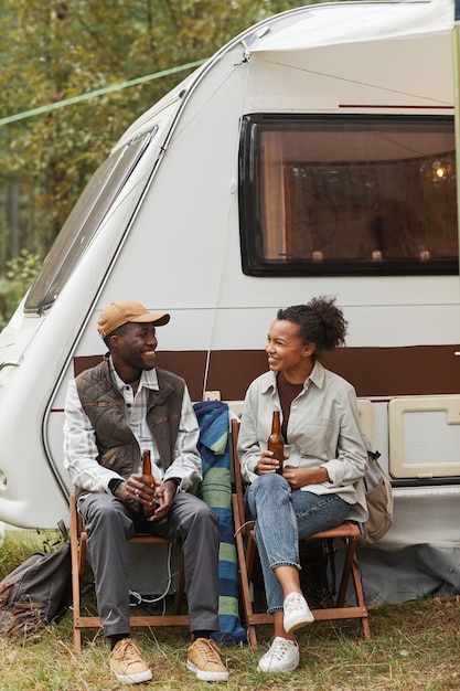Foto tiro vertical de cuerpo entero de la joven pareja afroamericana relajarse al aire libre mientras acampa con sendero ...