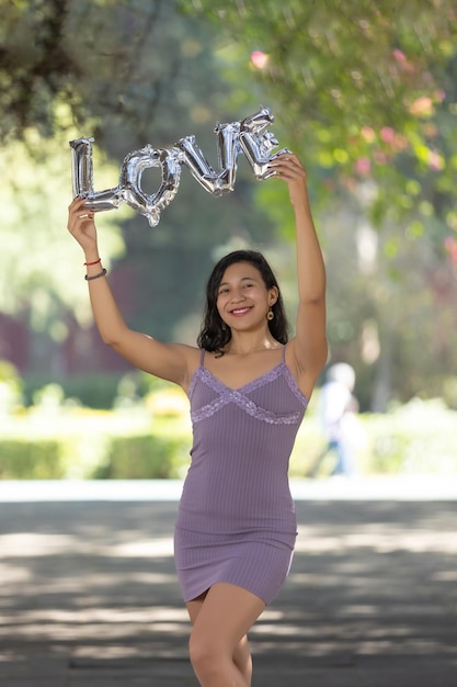 Tiro vertical da morena mexicana segurando cartas de balão de amor conceito de amor próprio do dia da mulher