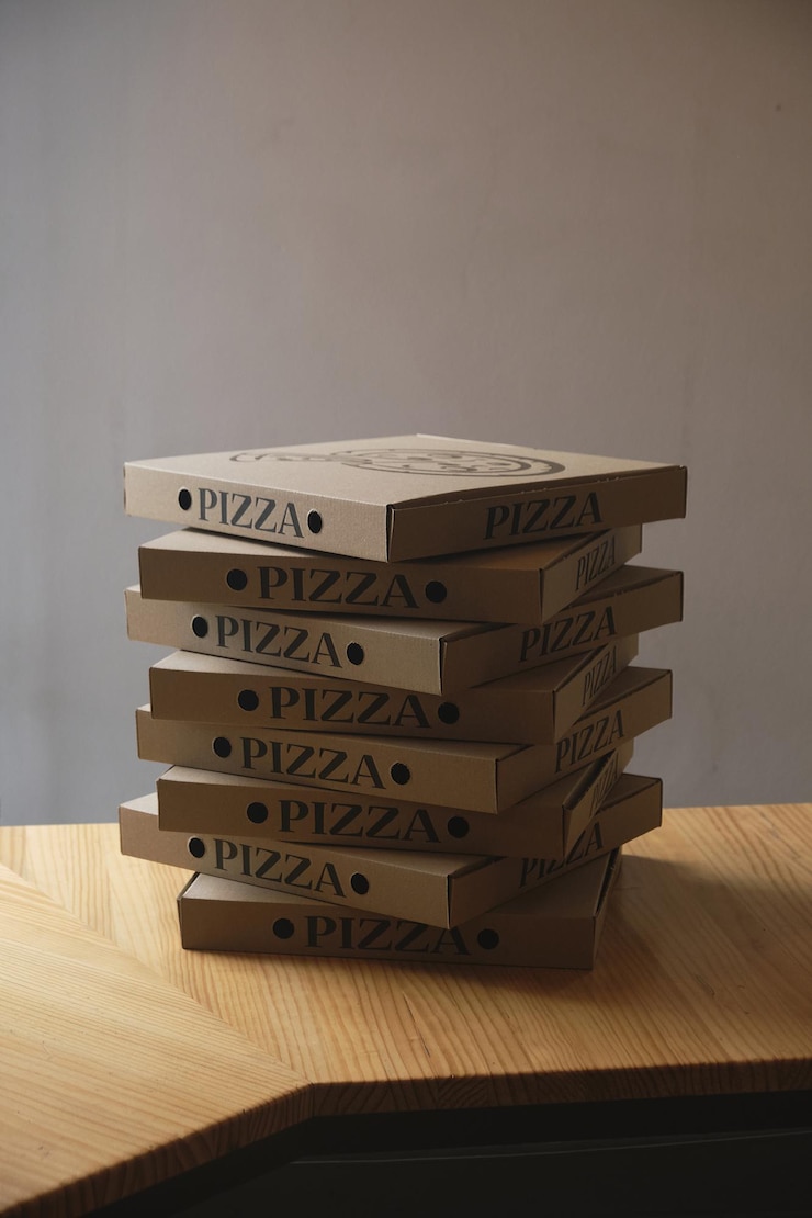 Foto tiro vertical de caixas de pizza de papelão empilhadas em uma mesa de madeira