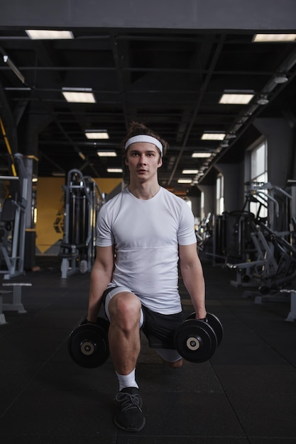 Tiro vertical de comprimento total de um atleta do sexo masculino fazendo lunges com halteres