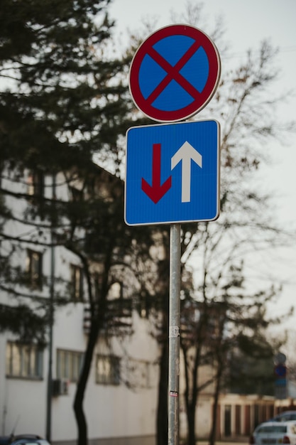 Tiro vertical de dois sinais de trânsito de formas diferentes na rua.