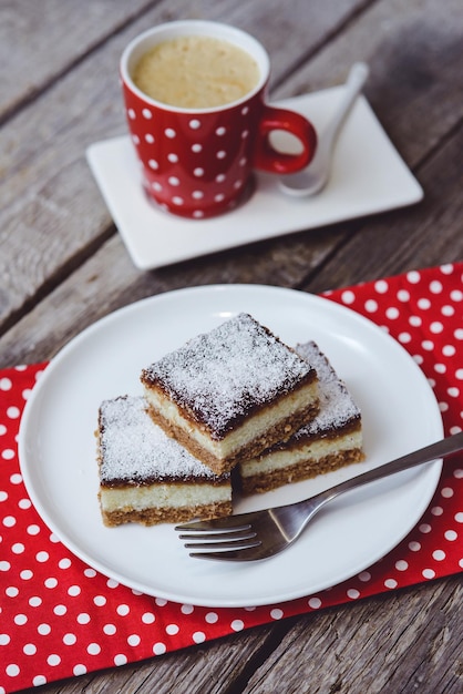 Tiro vertical de pedaços de bolo de chocolate em um prato branco com uma xícara de café