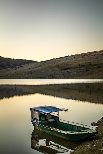 Tiro vertical de um barco no lago calmo durante o pôr do sol