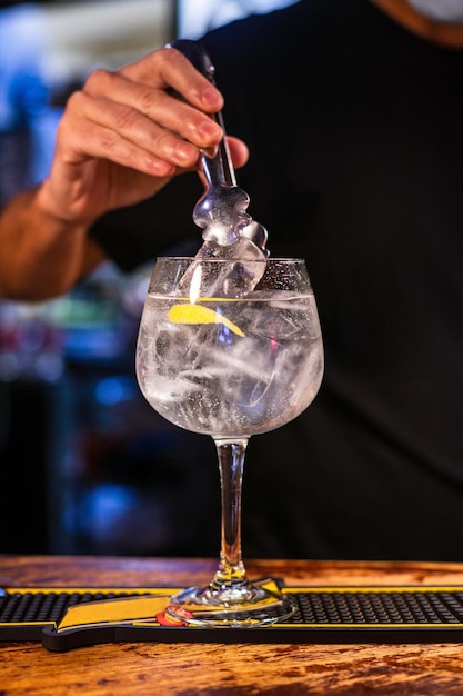 Foto tiro vertical de um barman preparando gin tônica