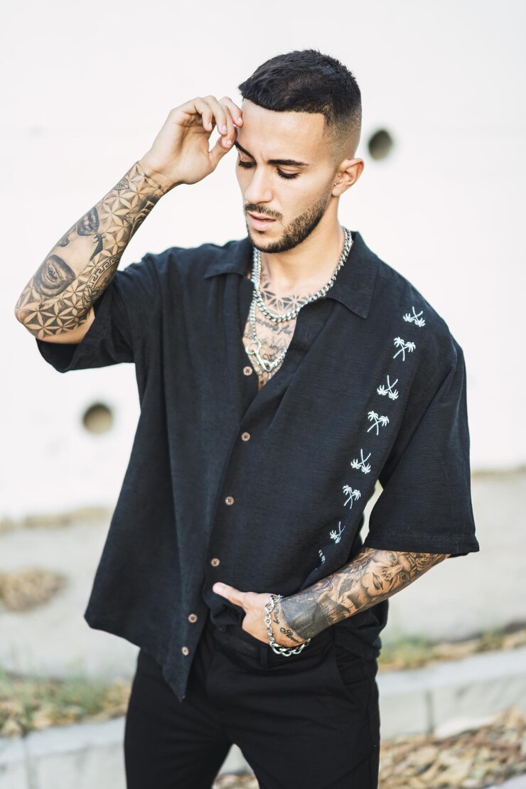 Foto tiro vertical de um homem europeu legal com tatuagens posando com um fundo de edifício
