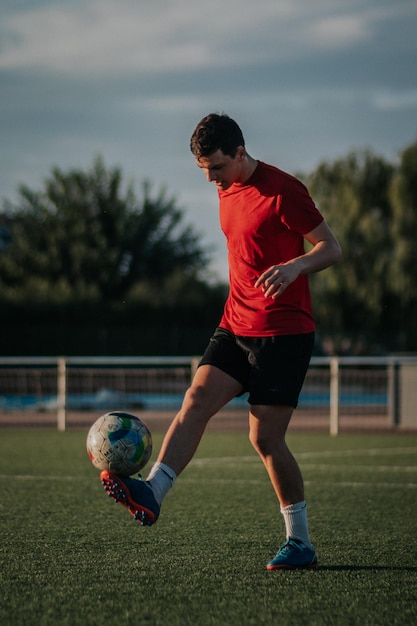 Tiro vertical de um jogador fazendo toques com os pés no campo de futebol.