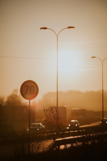 Tiro vertical de um sinal de trânsito redondo de limite de velocidade na estrada ao pôr do sol