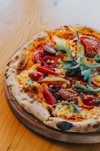 Tiro vertical de uma deliciosa pizza fresca com molho e legumes em uma bandeja sobre a mesa