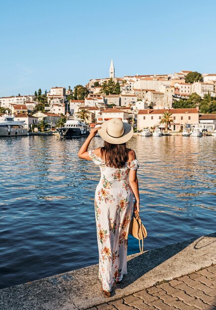 Tiro vertical de uma garota usando um chapéu e um vestido longo e posando em Trogir Croácia