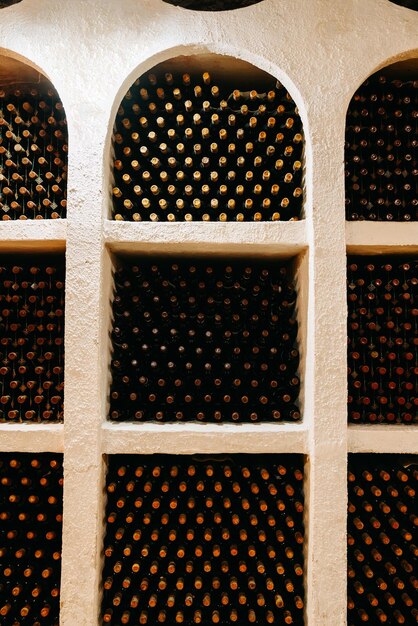 Foto tiro vertical de muchas botellas de vino almacenadas por colores en estantes de arco