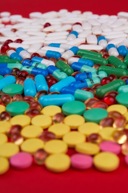 Tiro vertical muitos medicamentos coloridos diferentes e drogas de pílulas em fundo vermelho