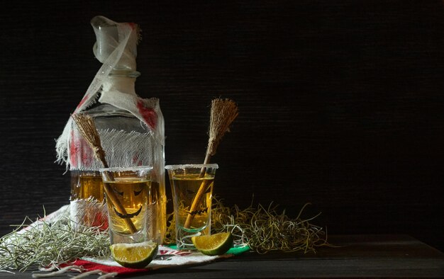 Tiros de tequila com decoração de halloween copos de garrafa enfaixados com rostos assustadores e vassouras de bruxa