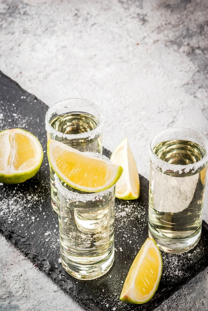 Tiros de tequila com limão e sal marinho na mesa de pedra cinza