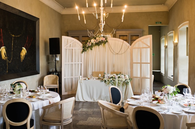 Tisch beim Hochzeitsbankett im Restaurant, klassischer Stil mit weißen Tischdecken und Servietten, Vasen mit Blumen.