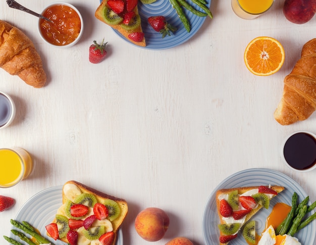 Tisch mit Frühstück - Spargel mit pochierten Eiern, Toast mit Obst, Croissants, Kaffee, Saft