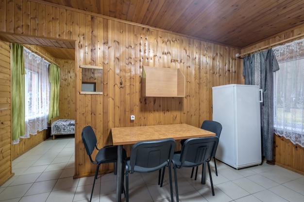 Tisch mit Stühlen und Sofa in der Eingangshalle des Gästezimmers in einem hölzernen Eco-Haus