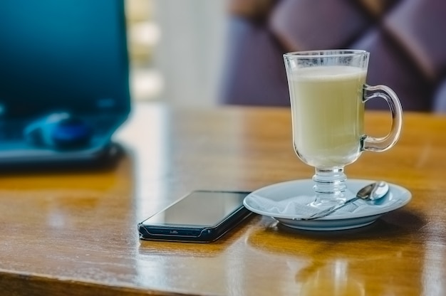 Tisch mit Tasse Latte Kaffee und Computer. Eine Tasse Latte in einem Café