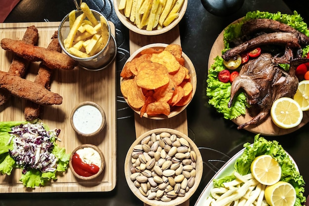 Tisch mit Teller mit Essen und Schüsseln mit Pommes Frites