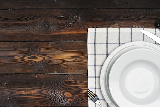 Tischaufbau mit Tellern auf dunklem Holzhintergrund